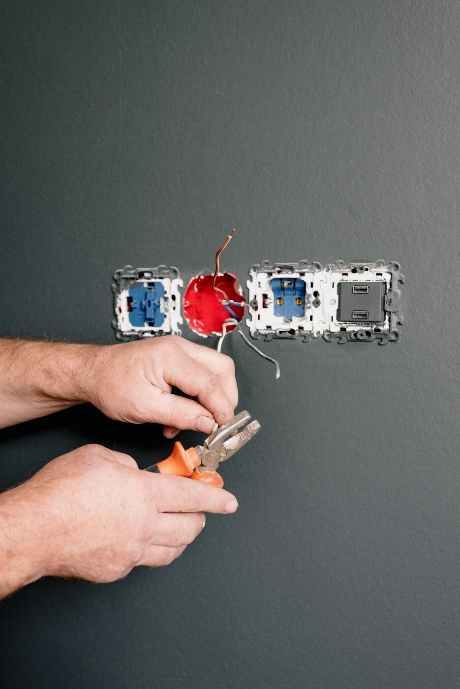 Electrician completing residential wiring at a wall outlet